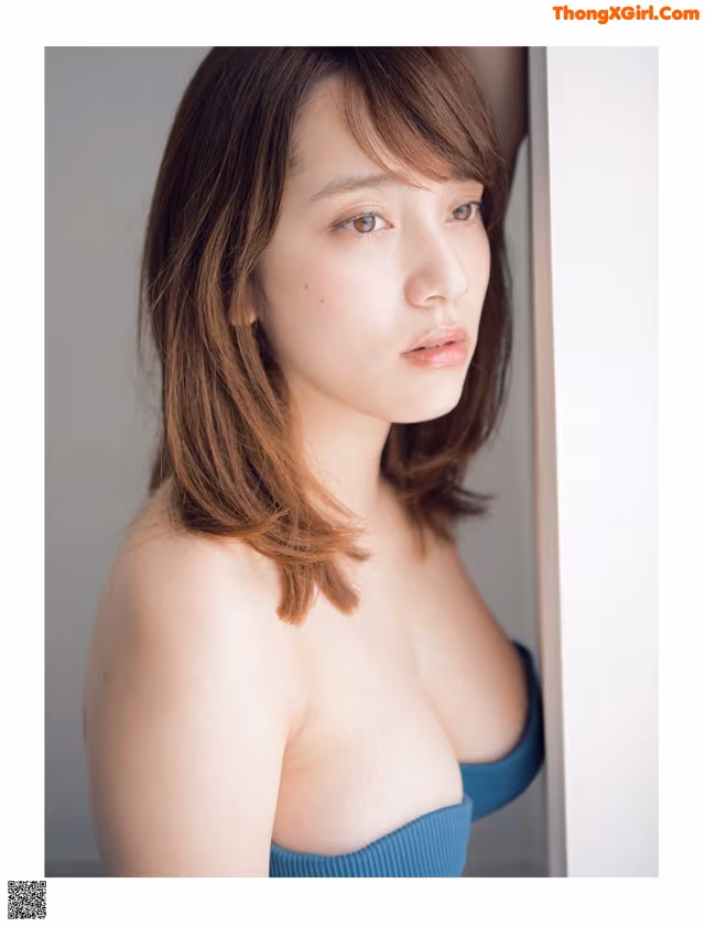 A woman in a blue dress leaning against a wall.