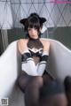 A woman in a black and white outfit sitting in a bathtub.