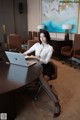 A woman sitting at a table with a laptop computer.