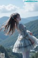 A woman in a dress standing on top of a hill.