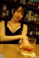 A woman sitting at a bar with a glass of whiskey.