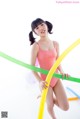 A woman in a pink bathing suit holding a hula hoop.