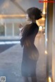 A woman in a black dress standing in front of a window.