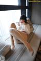 A woman sitting on a couch with her legs crossed.