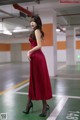 A woman in a red dress standing in a parking garage.