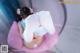 A little girl sitting in a pink chair with her feet up.