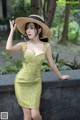 A woman in a yellow dress and straw hat posing for a picture.