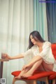 A woman sitting on a red chair next to a glass of water.