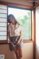 A woman standing in front of a window in a room.