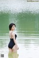 A woman in a black bathing suit standing in the water.