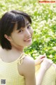 A woman in a yellow dress sitting in a field of flowers.