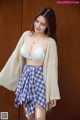 A woman in a white bra top and plaid skirt posing for a picture.