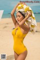 A woman in a yellow swimsuit with a towel on her head.