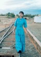 A woman in a blue dress standing on a train track.