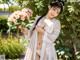 A woman in a white kimono holding a bunch of flowers.