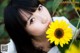 A woman is smelling a yellow flower in a field.