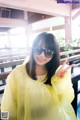 A woman in a yellow raincoat and sunglasses posing for a picture.