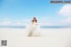 A woman in a wedding dress standing on a beach.