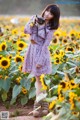 A woman standing in a field of sunflowers holding a camera.