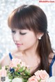 A woman in a blue dress holding a bouquet of flowers.