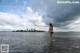 A woman in a black bikini standing in the water.