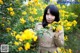 A woman standing in front of a bush of yellow flowers.