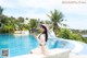 A woman sitting on the edge of a swimming pool holding a tablet.